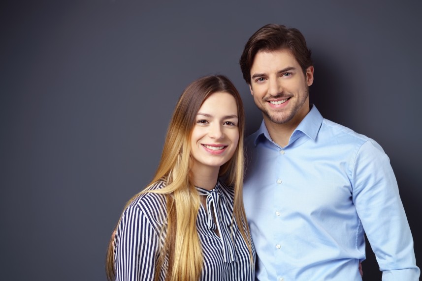 Happy,Attractive,Young,Couple,Posing,Arm,In,Arm,Against,A